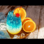 Kenny Cooler cocktail with blue and turquoise layers, ice, and fruit garnish